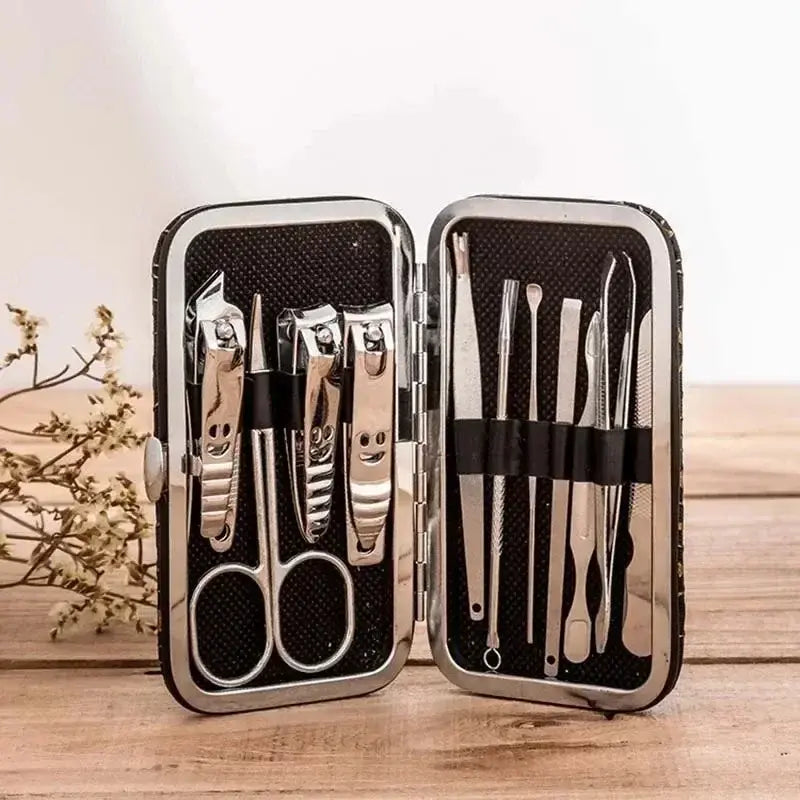 Manicure set with scissors, clippers, and tweezers in a black case on a wooden surface.