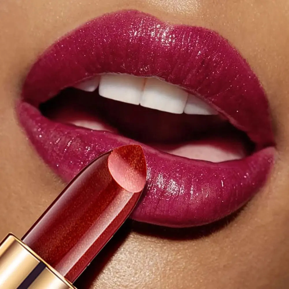 Close-up of a person applying a deep pink lipstick with a gold applicator.