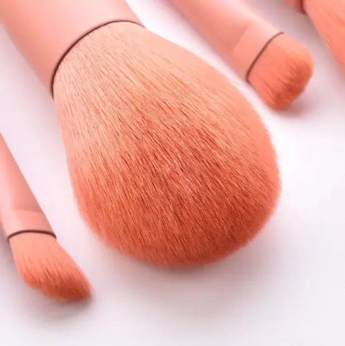 Set of makeup brushes with orange bristles on a white background