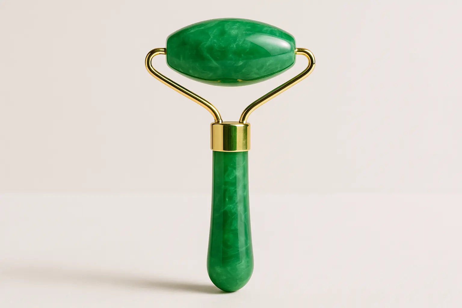 Green jade roller with gold accents on a light beige background