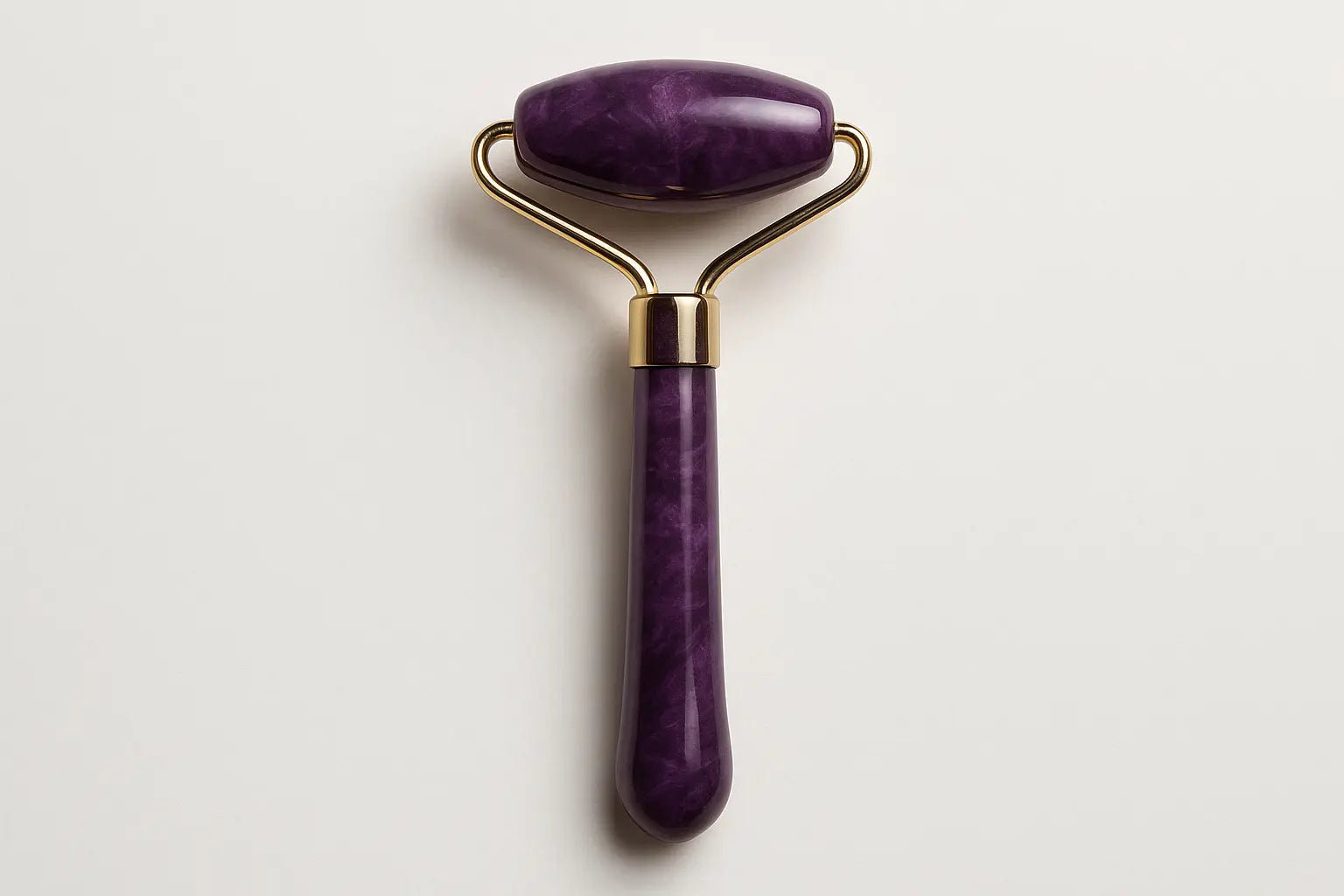 Purple facial roller with gold accents on a light gray background